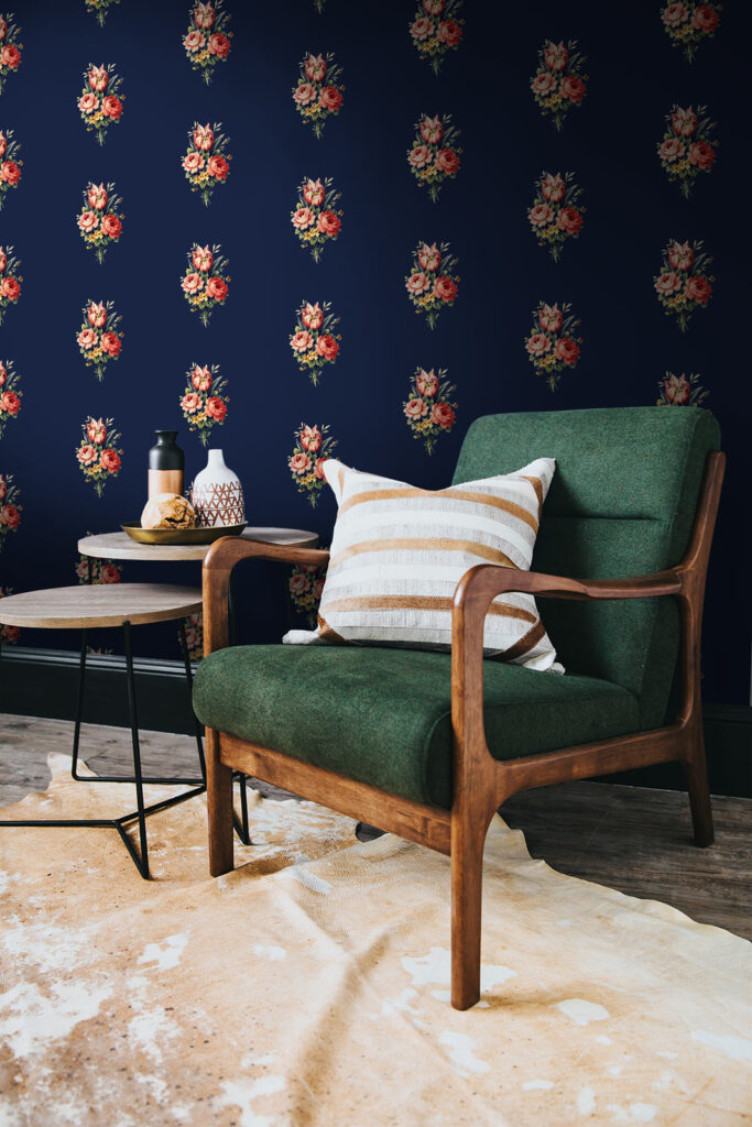 Navy blue floral wallpaper set into a living room feature wall along with green armchair. Baubauwall wallpapers