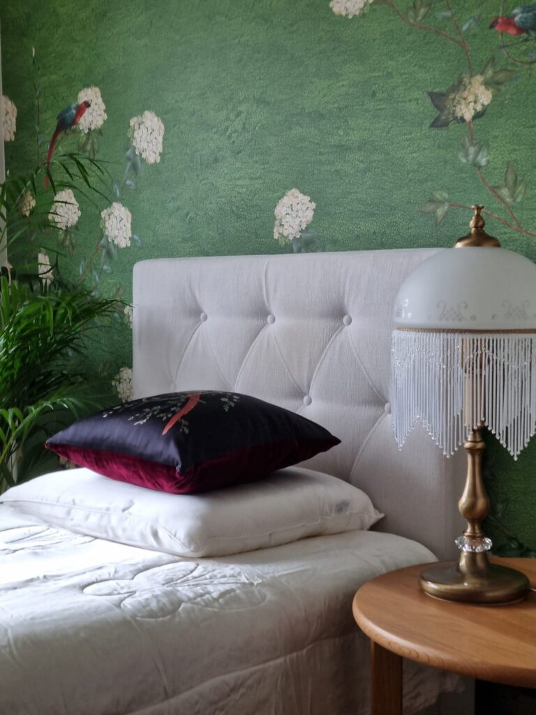 Green chinoiserie mural wallpaper on a bedroom feature wall